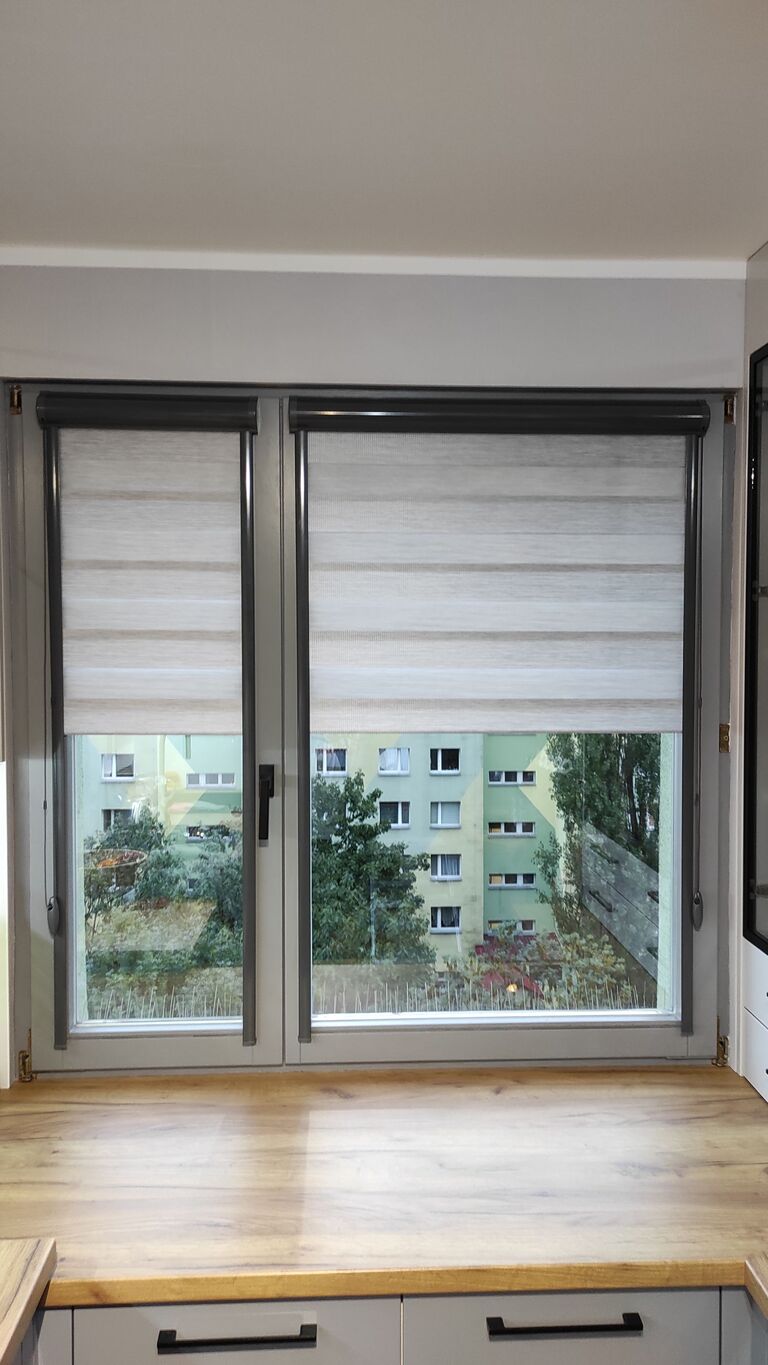 Doppel-Kassettenrollo zum Kleben am Fensterrahmen mit Seitenschienen. 